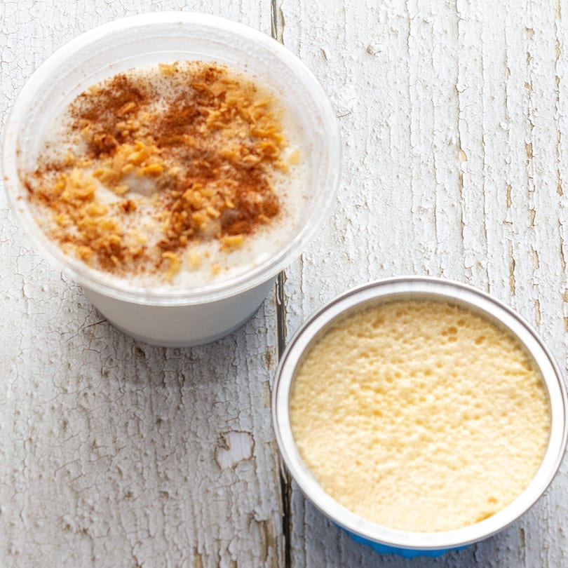 Two Puerto Rican desserts, one topped with cinnamon and nuts, on a distressed white wooden surface.